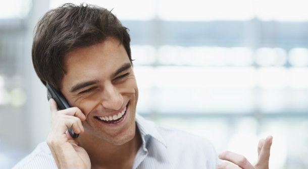 Laughing young guy enjoying a conversation over the cellphone